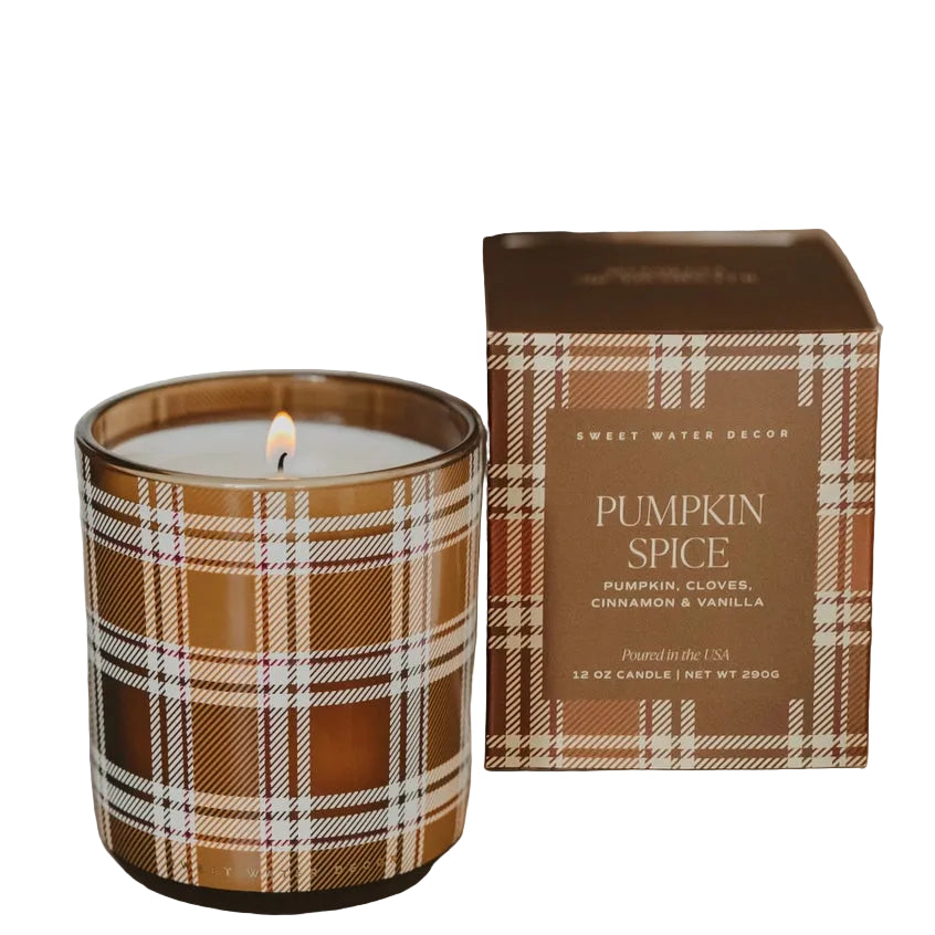 A lit candle in a brown plaid glass jar sits next to its matching retail box with a white background. The box reads 'Sweet Water Decor' and 'Pumpkin Spice'.