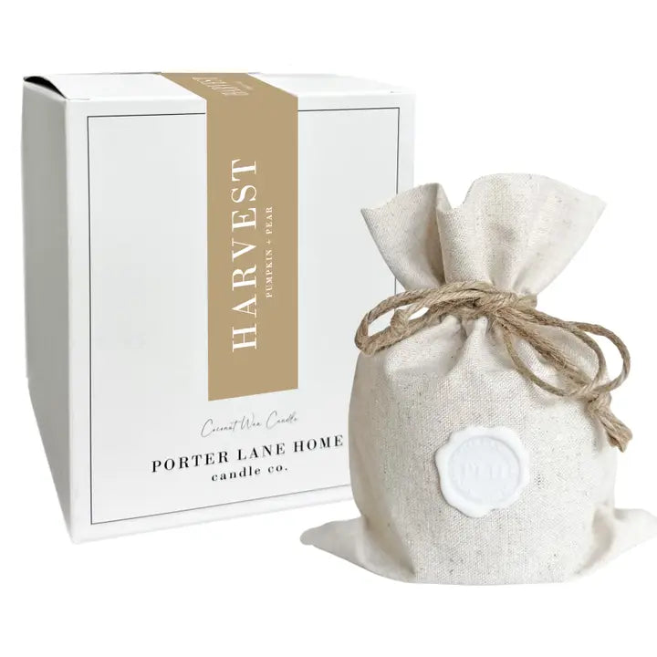 A white square product box with a tan vertical band reading HARVEST PORTER LANE HOME candle co. stands beside a small natural-fabric drawstring pouch tied with twine and sealed with a white wax seal, on a white background.