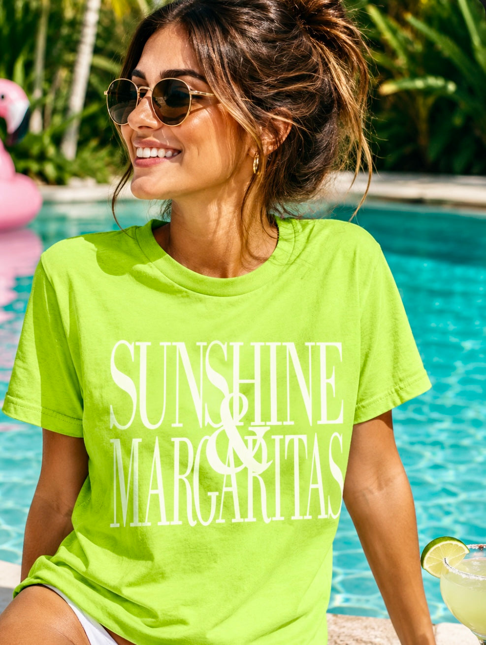 Woman wearing a bright green 'Sunshine & Margaritas' t-shirt by a pool.