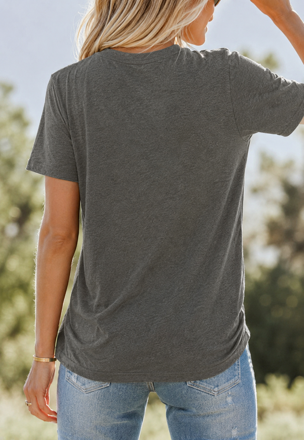 Person wearing a gray t-shirt and blue jeans with a blurred natural background