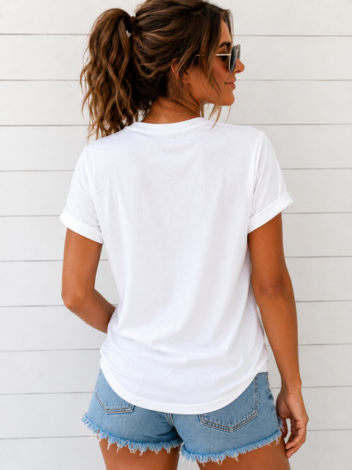 Woman wearing a white t-shirt and denim shorts against a light wooden background