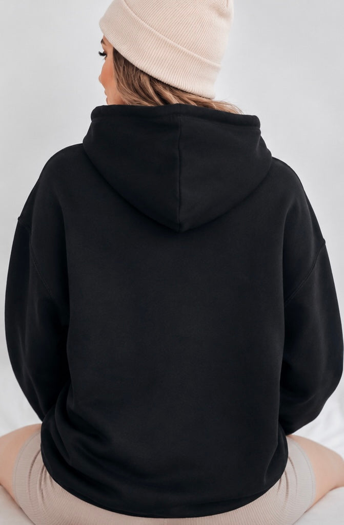 Person wearing a black hoodie and beige beanie on a white background