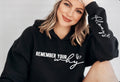 Woman wearing a black hoodie with 'Remember Your Why' text on a plain background