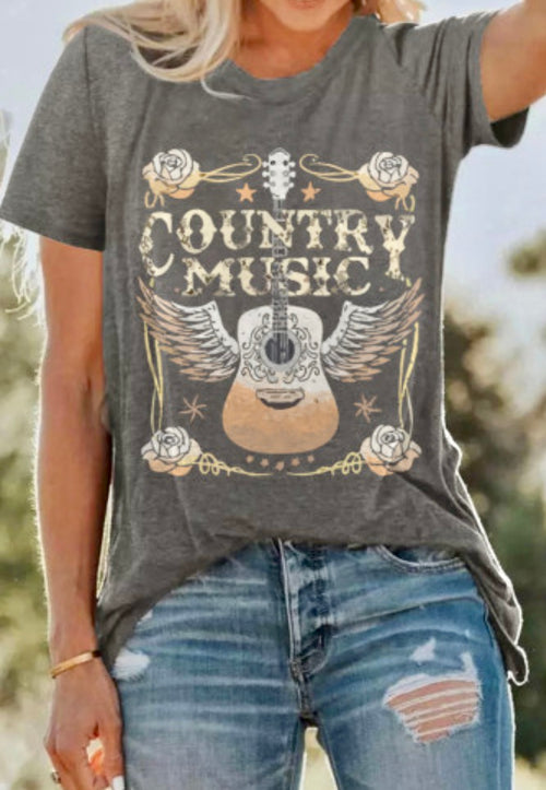 Person wearing a gray t-shirt with 'Country Music' and guitar design outdoors.