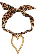 A leopard print fabric headband tied in a bow at the top, featuring a textured gold heart-shaped metal pendant hanging from the center, shown against a plain white background.