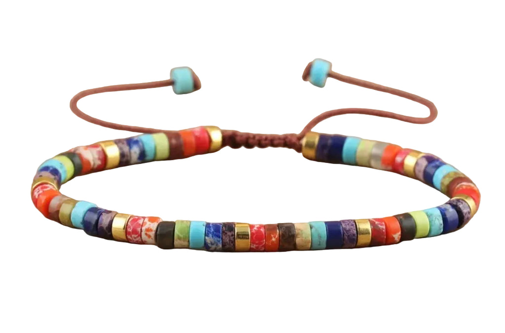 A beaded adjustable cord bracelet with colorful cylindrical beads in red, blue, yellow, green, black, and white, accented by gold-toned metal rings, displayed on a white background. 
