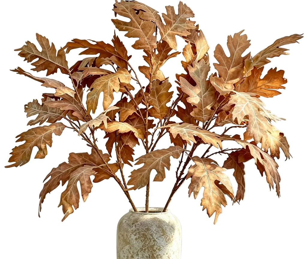 A decorative arrangement of dried brown oak leaves in a textured off-white ceramic vase against a white background.