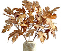 A decorative arrangement of dried brown oak leaves in a textured off-white ceramic vase against a white background.