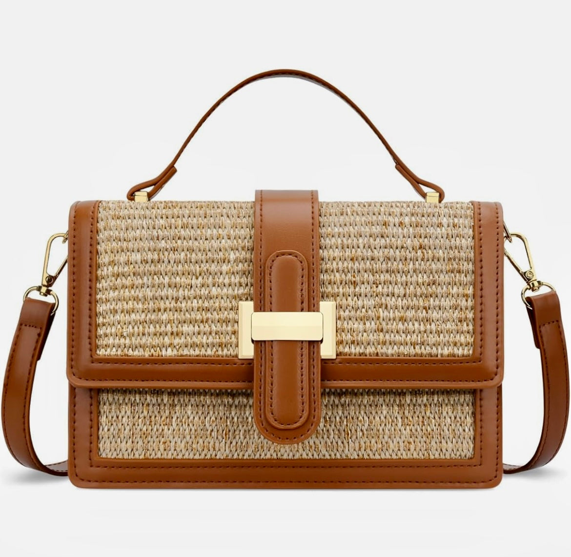 A structured woven straw handbag with tan leather trim, a top handle, and a gold-tone metal accent on the front flap, shown against a light gray background.