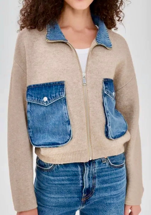 A cropped beige knit zip-up cardigan with contrasting blue denim pockets and collar, worn by a model with blue jeans.