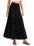 A black tiered maxi skirt worn by a model, paired with black strappy sandals and a white crop top, shown against a plain white background.