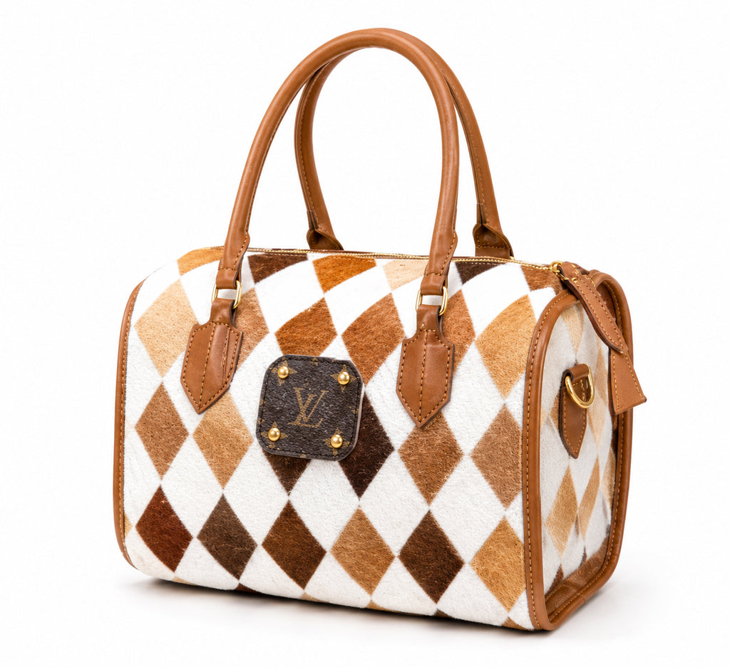 Upcycled Louis Vuitton handbag featuring a brown and white argyle patterned hair-on-hide body with tan leather handles and trim, and a dark brown LV logo plaque on the front.