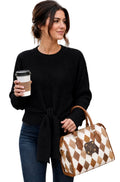 A woman wearing a black ribbed knit sweater and blue jeans holding a brown and white checkered Louis Vuitton duffel bag and a coffee cup.