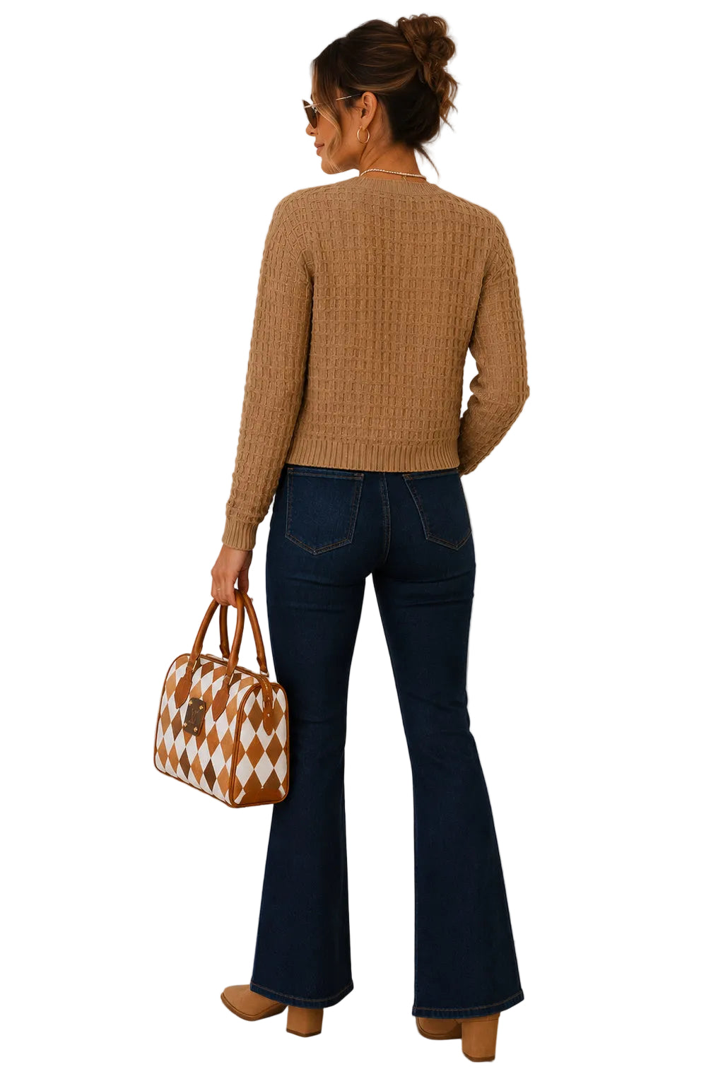 A woman is shown from behind wearing a tan ribbed knit sweater, dark blue flare jeans, and tan shoes, holding a brown and white diamond-patterned handbag with a white background.