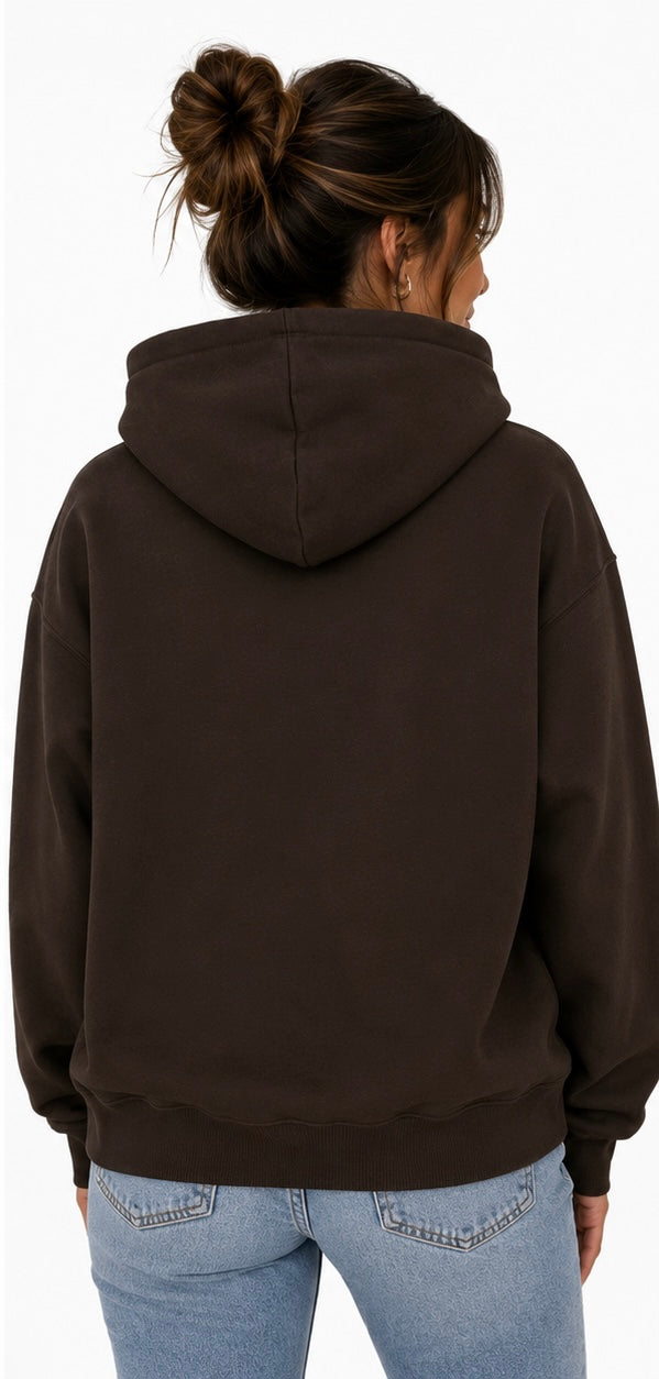 A woman viewed from the back wearing a dark brown pullover hoodie and light blue jeans against a plain white background.