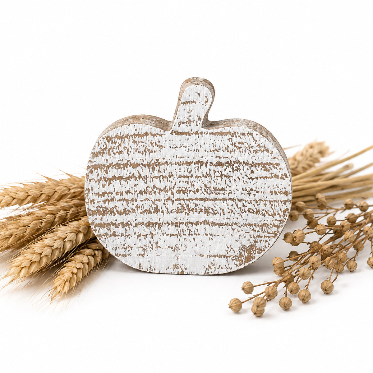 A distressed white and brown faux-wood pumpkin-shaped decorative sign styled with dried wheat stalks and baby's breath on a white background.