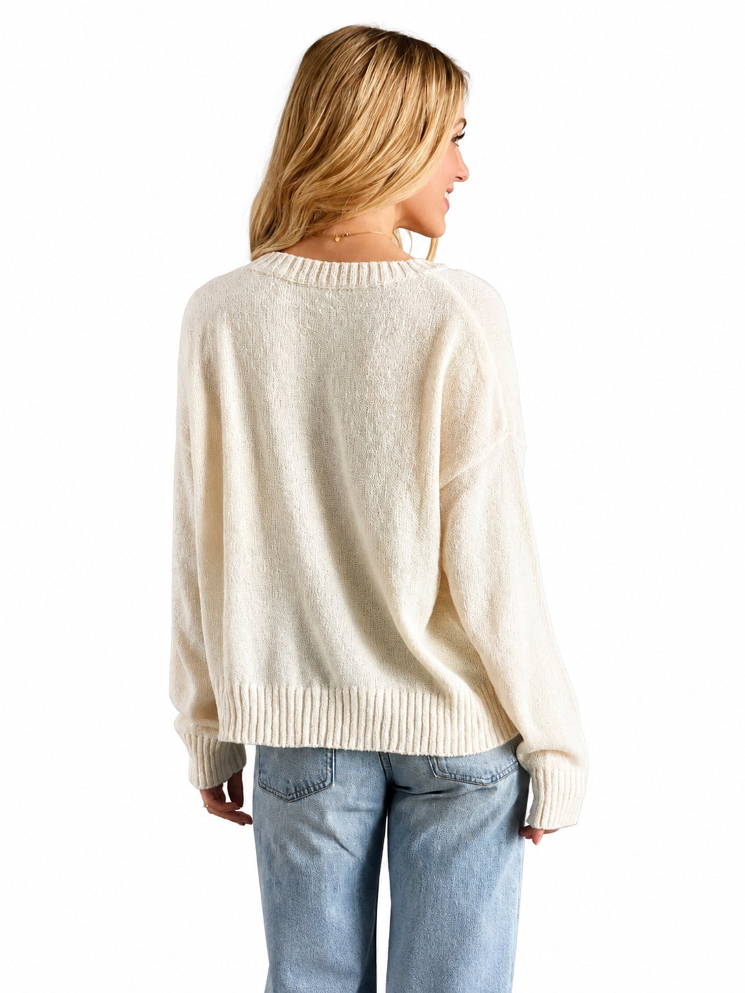 A woman shown from the back wearing a cream-colored knit sweater and light blue jeans against a plain white background.