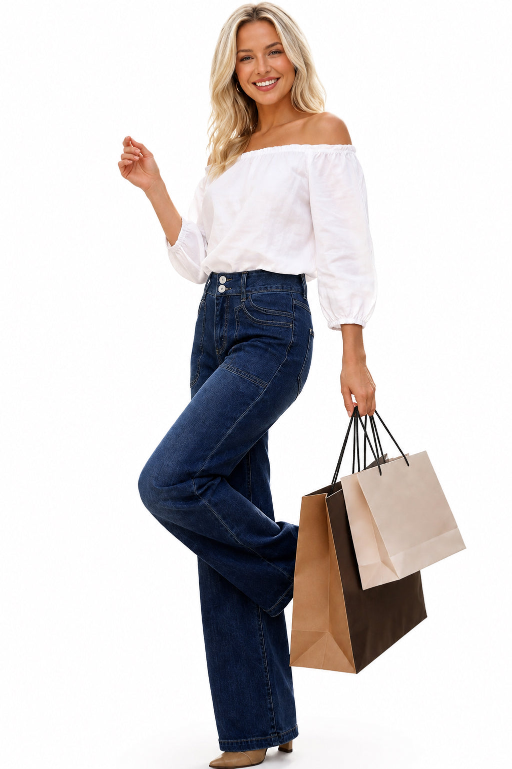 A woman modeling an off-the-shoulder white puff-sleeve blouse and dark blue wide-leg jeans, holding brown and beige shopping bags against a solid white background.