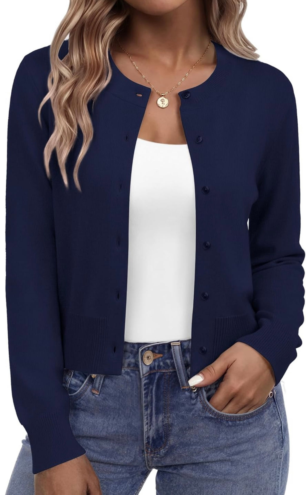 A woman wearing a navy blue button-up cardigan over a white tank top and blue jeans, shown from the neck down against a plain white background.