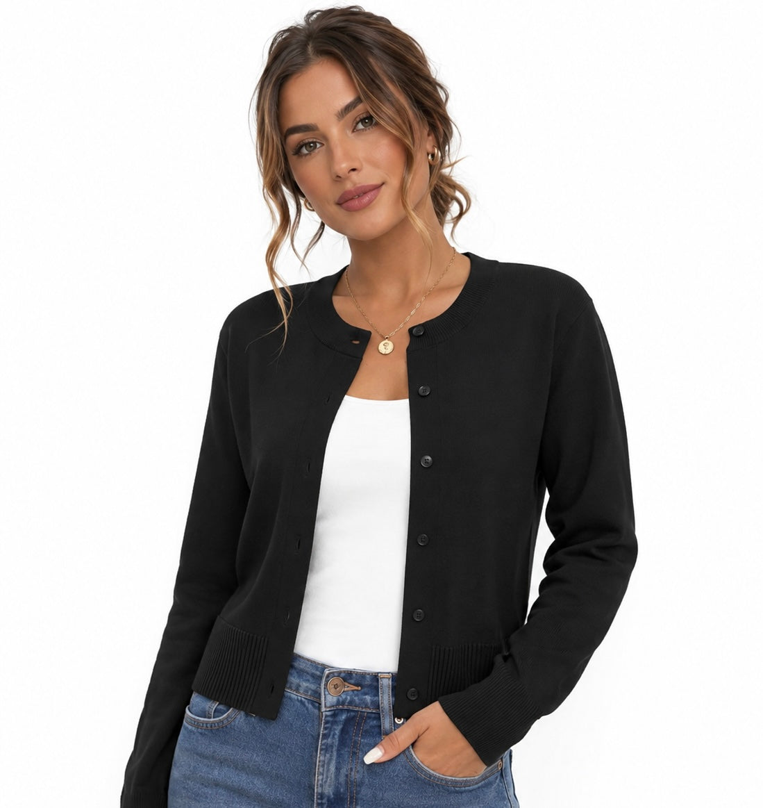 A woman wearing a black button-front cardigan over a white tank top and blue jeans, photographed against a clean white studio background.