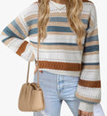 A woman wearing a cream, blue, and brown striped knit sweater with long sleeves, paired with light blue jeans and a beige crossbody bag, shown against a plain white background.