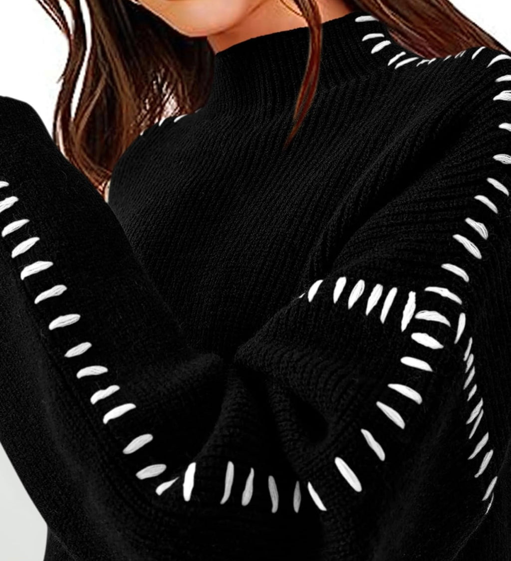 Close-up of a black ribbed knit sweater with white embroidered or contrast-stitched decorative accents along the sleeve seams, worn by a model.